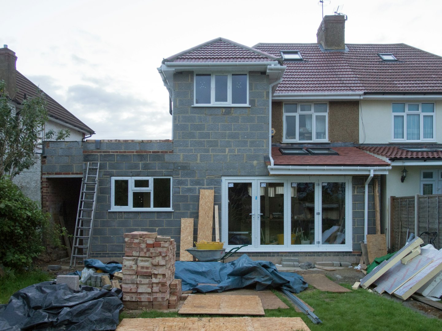 A house extension under construction with materials scattered across the yard.