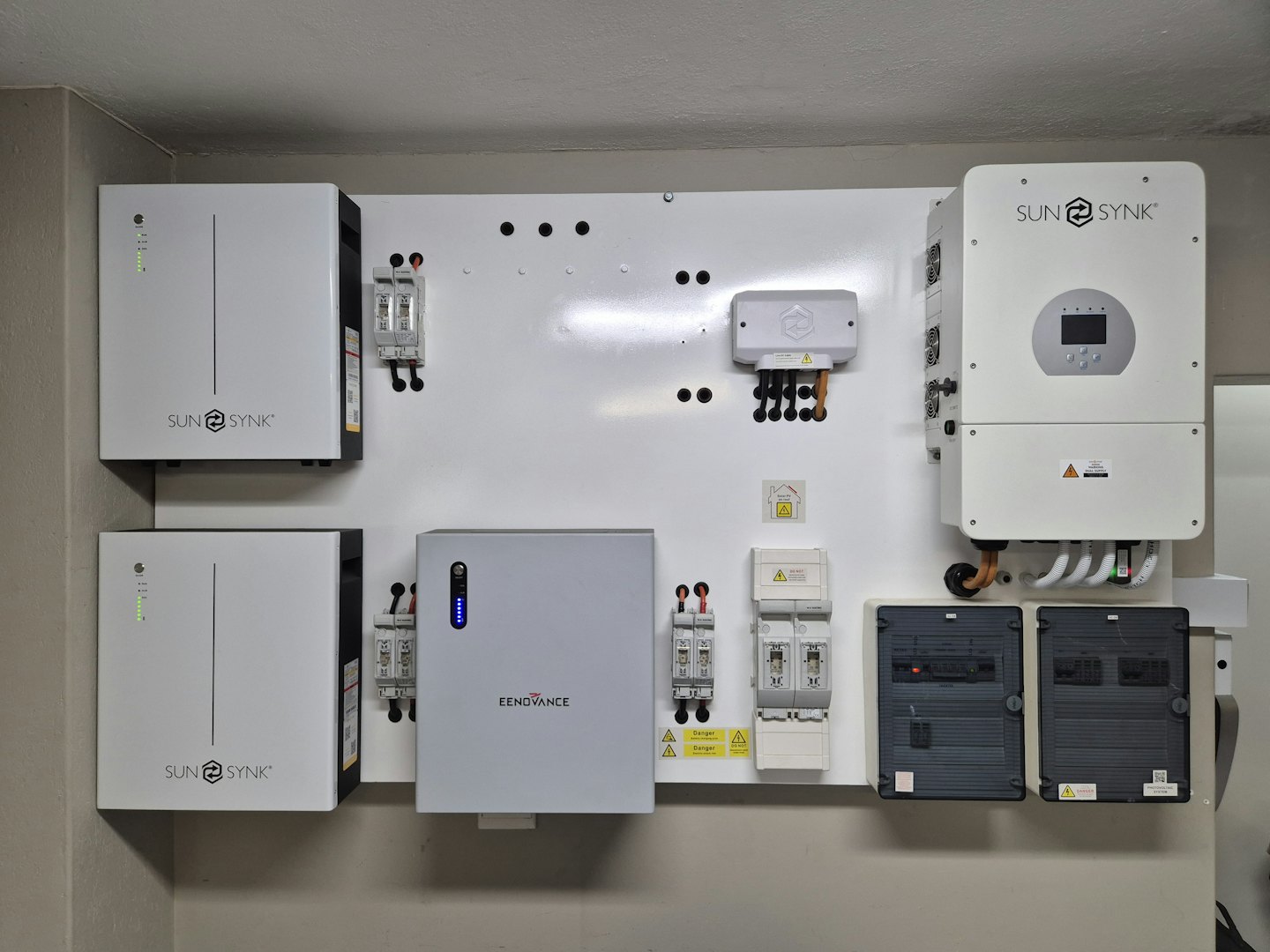 Home energy system with batteries and inverters on a white wall.
